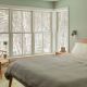 Bedroom in residential home with large white wood windows installed almost floor to ceiling